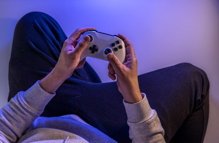 male-hands-hold-gamepad-blue-background-copy-space